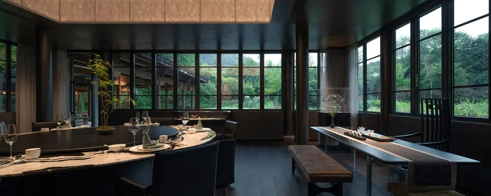Modern restaurant interior with large windows and wooden furniture.