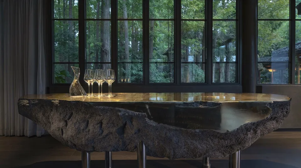 A modern table featuring a natural rock base with three wine glasses and a decanter.
