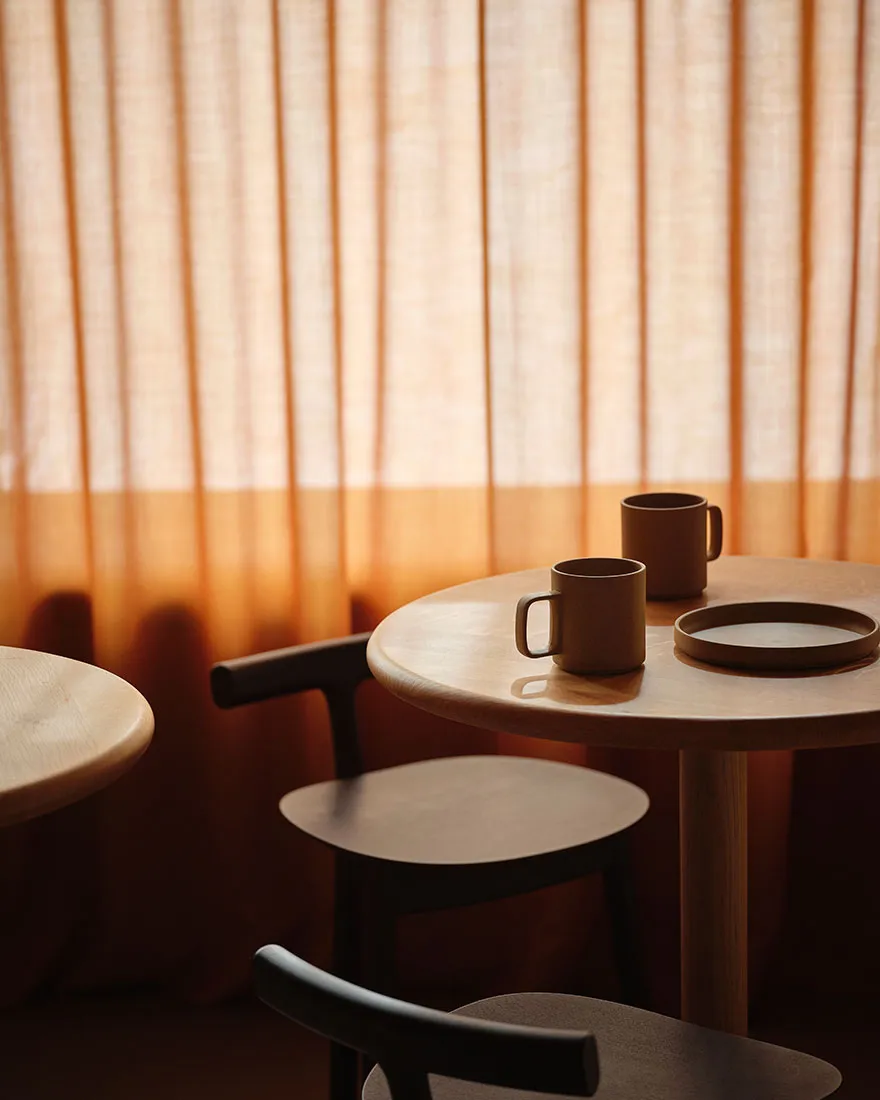 Two wooden tables with brown mugs and plates in a cozy cafe setting.