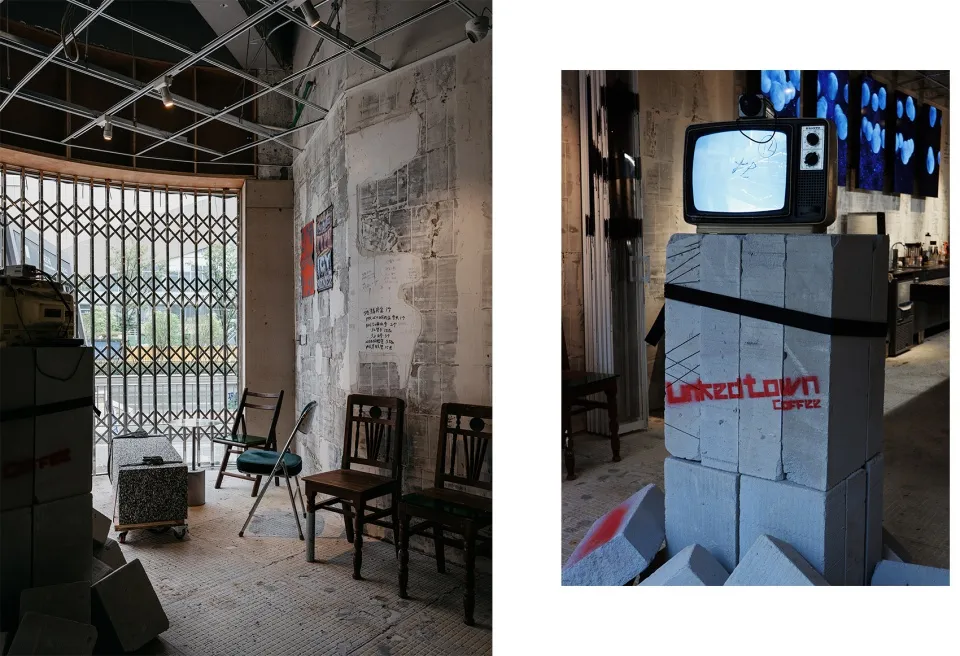Interior of a cafe with industrial-style decor, featuring concrete walls and a television mounted on a block structure.