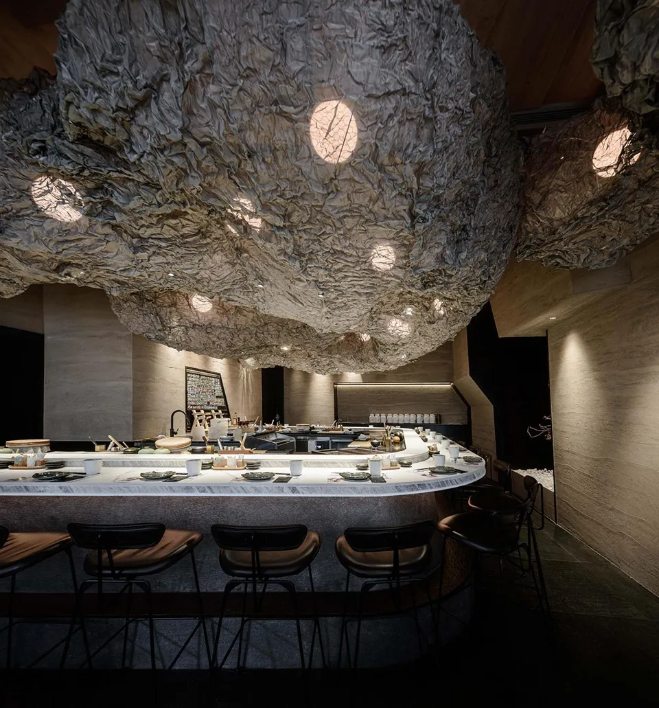 A modern restaurant bar counter with a textured fabric ceiling