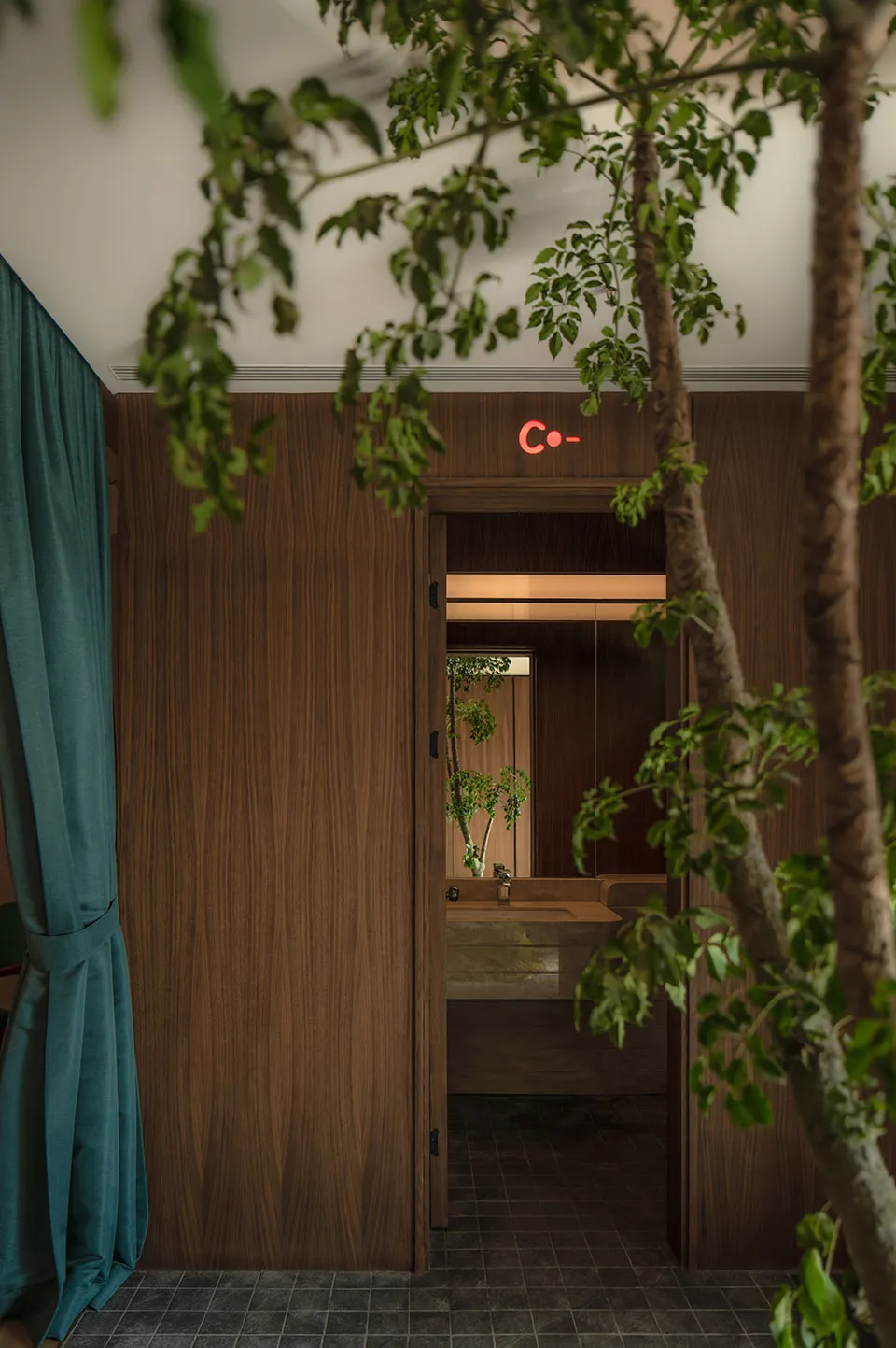 A modern restroom with wooden walls and a green plant, illuminated by soft lighting through a window.