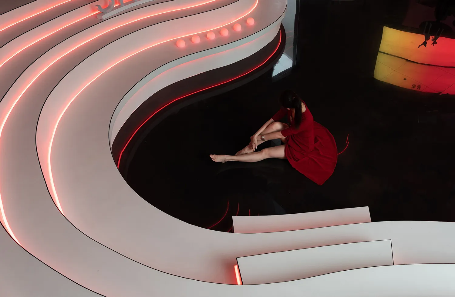 A modern interior space featuring glass and concrete materials with red and white lighting.