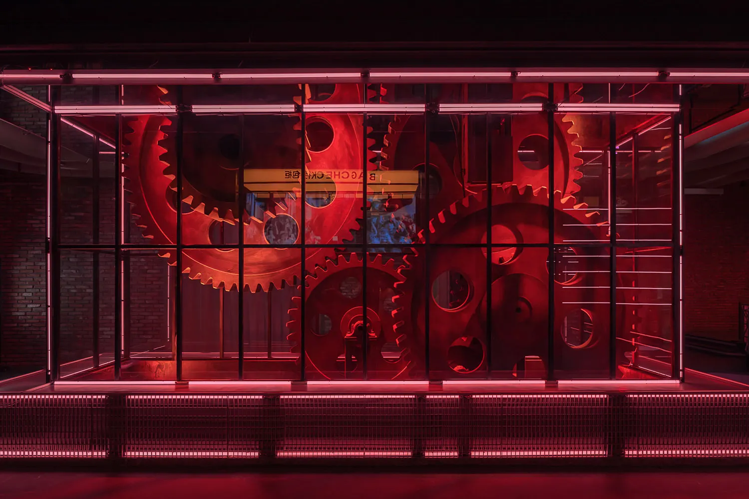 A modern art installation featuring rotating metal gears and neon lighting.