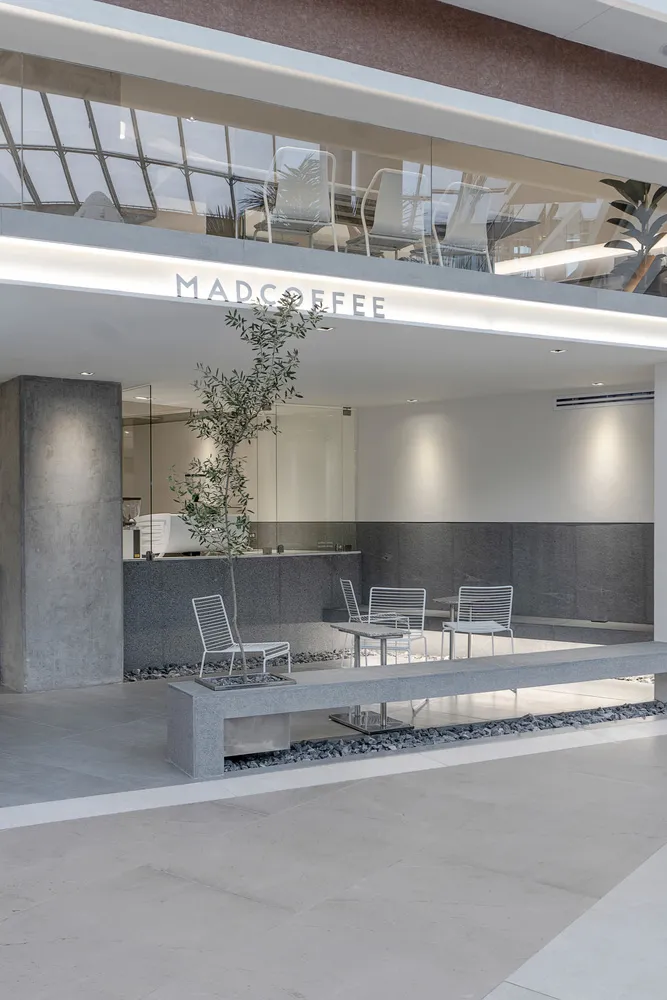 Modern coffee shop interior with minimalist design, featuring concrete and glass materials, and a sleek seating area with whi