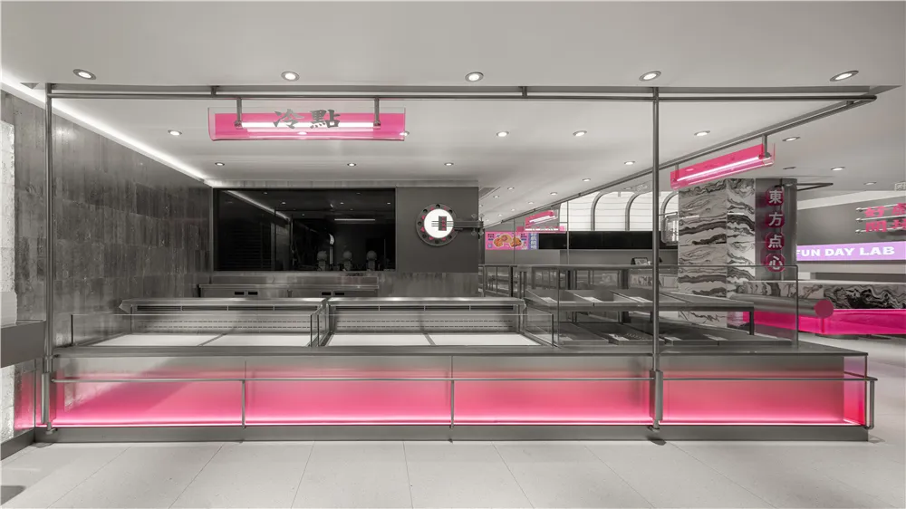 A sleek and modern coffee shop with metallic accents and pink lighting.