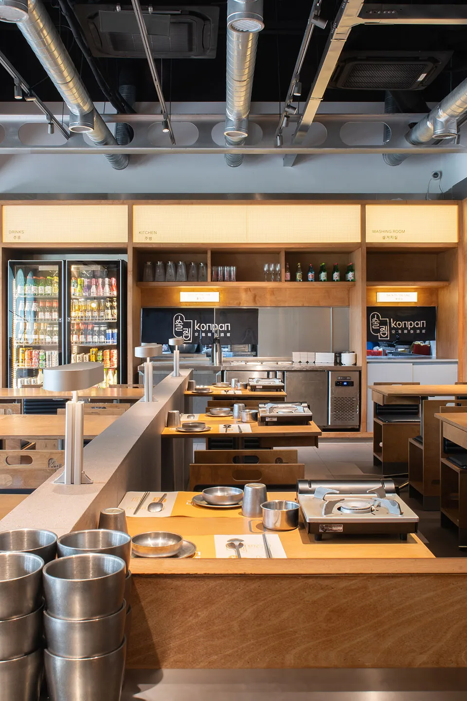 An interior view of a modern restaurant kitchen with wooden elements and stainless steel appliances.