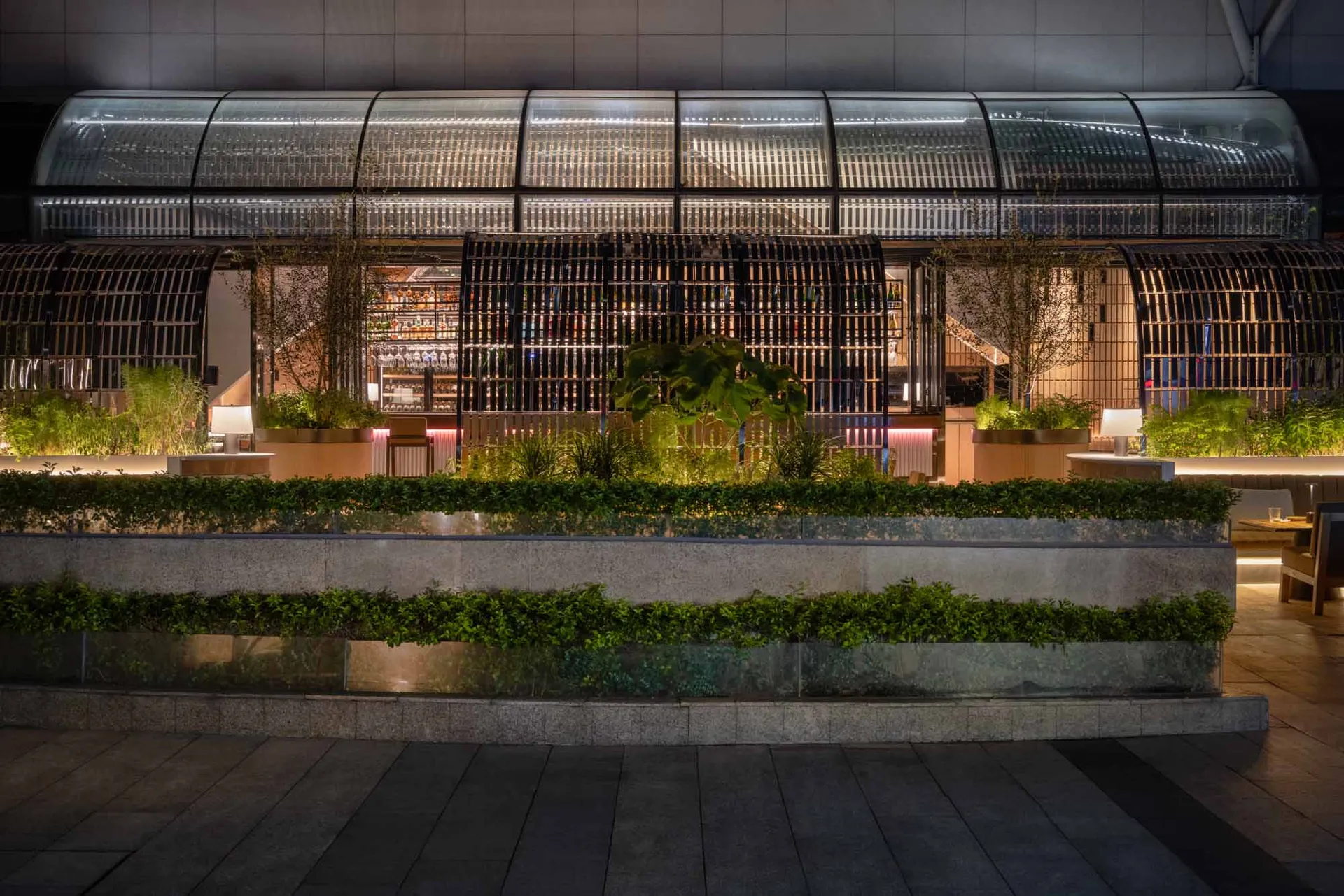 Modern industrial restaurant exterior with metal, glass, concrete, and greenery