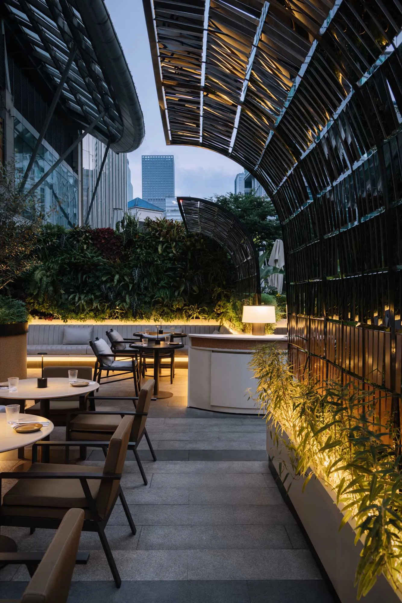 A modern restaurant with metal structures and greenery outdoors.