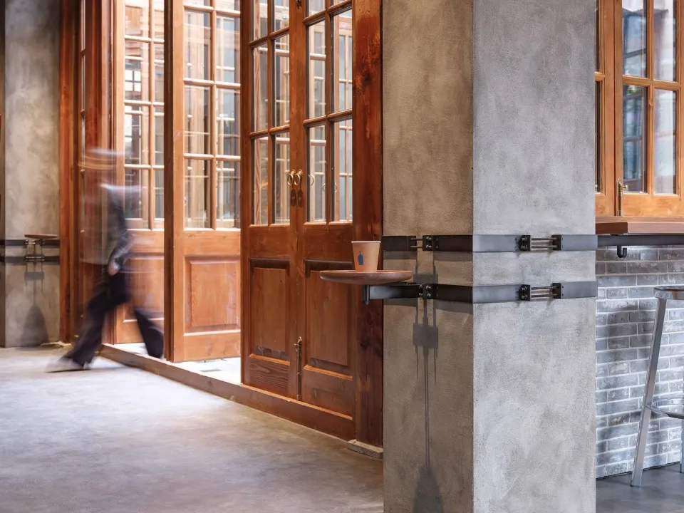 A modern coffee shop interior featuring a concrete floor, brick walls, and wooden accents.