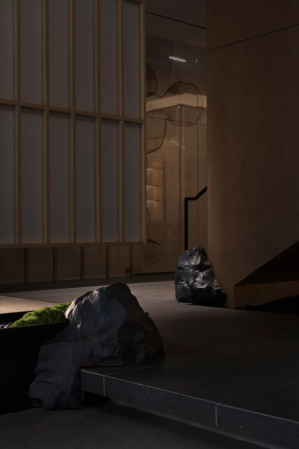 A minimalist interior space featuring concrete elements and dark stone rock decorations.