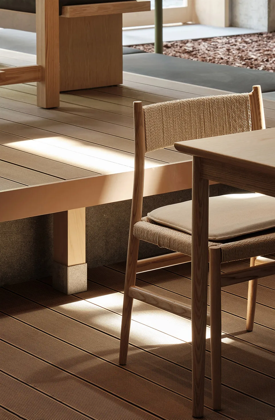 Minimalist interior design featuring wooden furniture with a woven rope backrest cushion.
