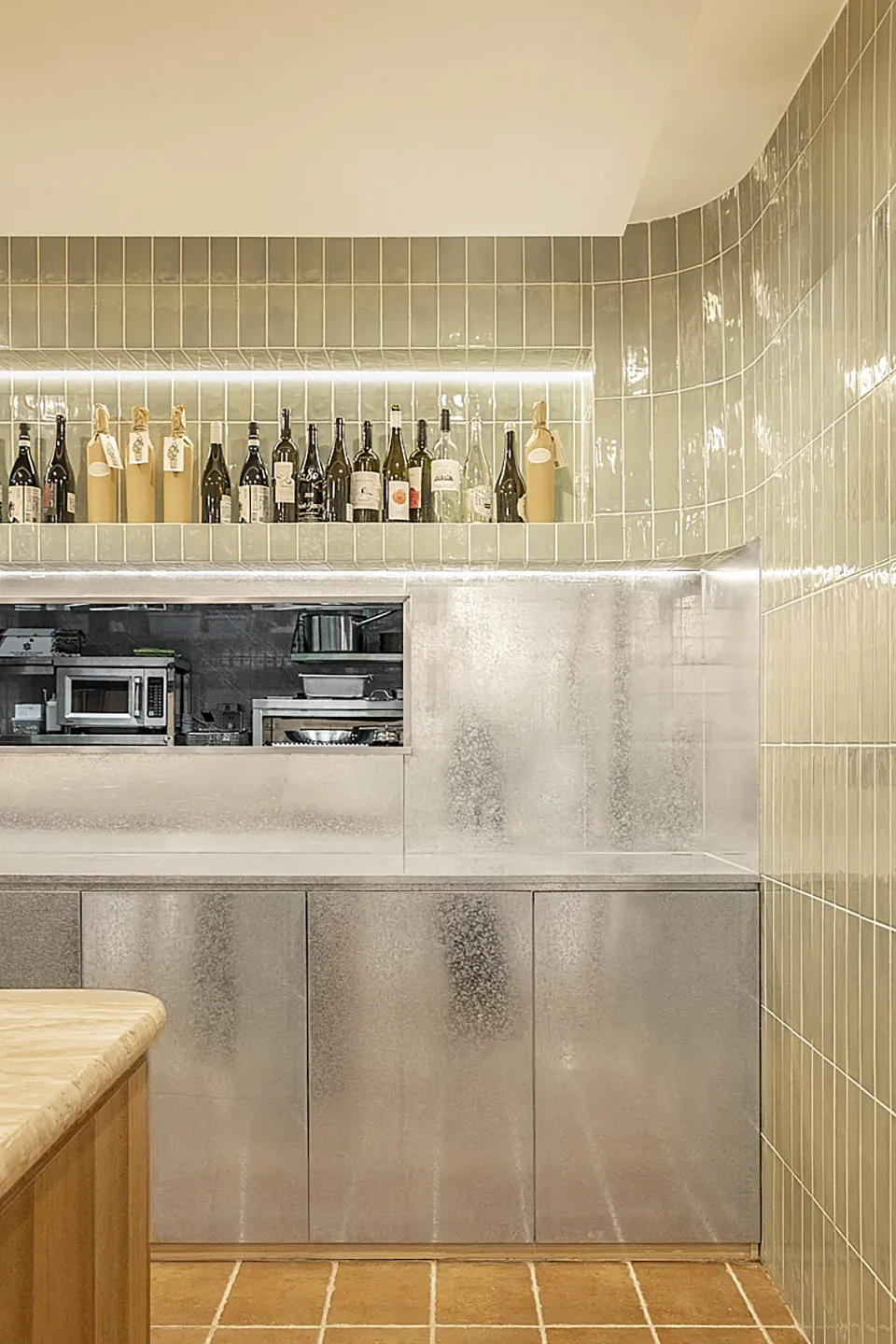 Modern kitchen interior with glass tiles on the wall and a concrete counter.