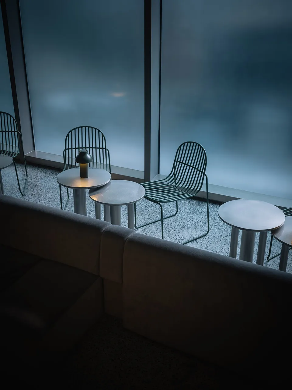 A modern restaurant interior with metal furniture and round tables.