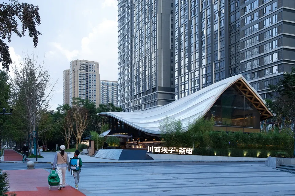 A modern urban architectural scene featuring metallic glass, concrete, and greenery.