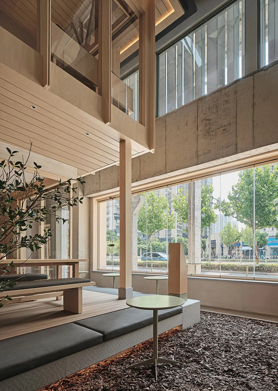 現代自助餐廳室內,配有木質長椅、混凝土牆面,以及大型玻璃窗。