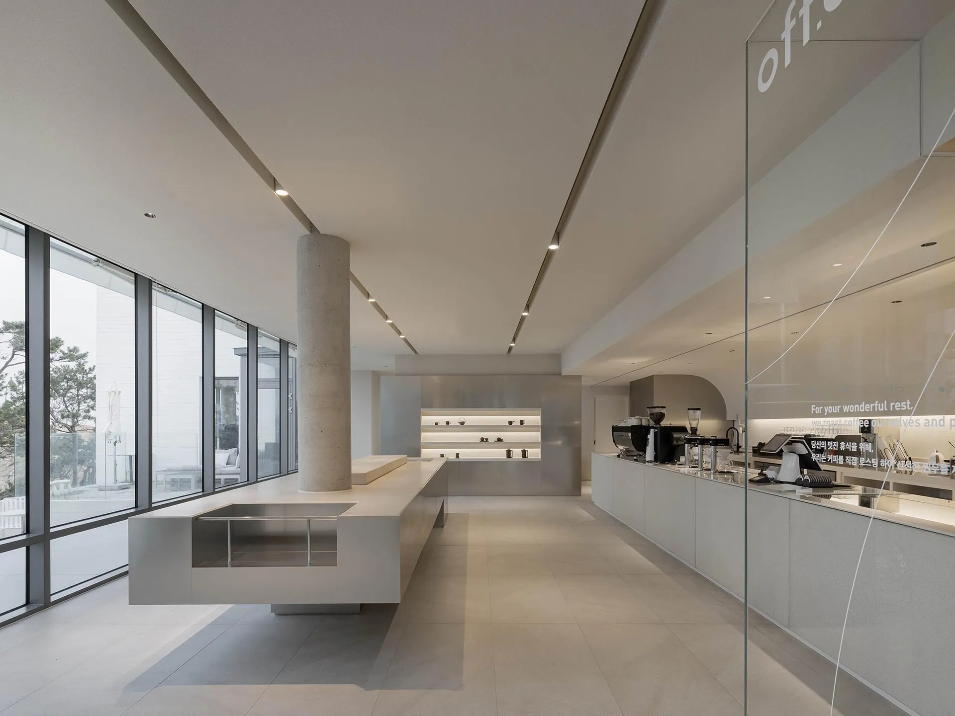 A modern coffee shop interior featuring concrete and glass materials.