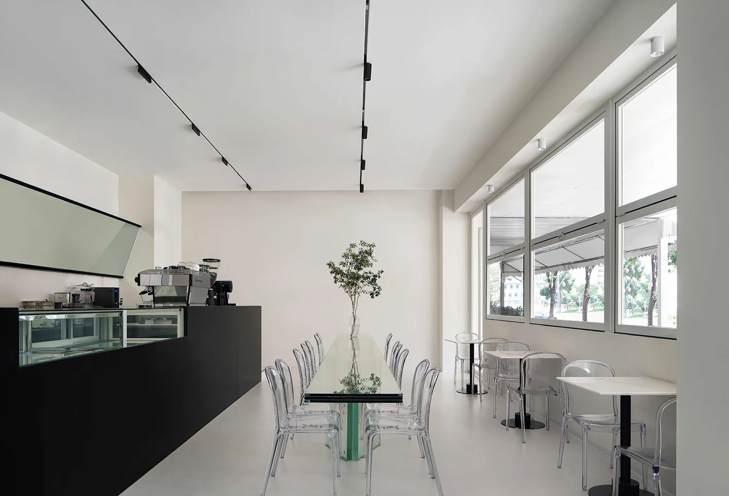 Modern cafe interior with glass tables, metal chairs, and minimalist design.