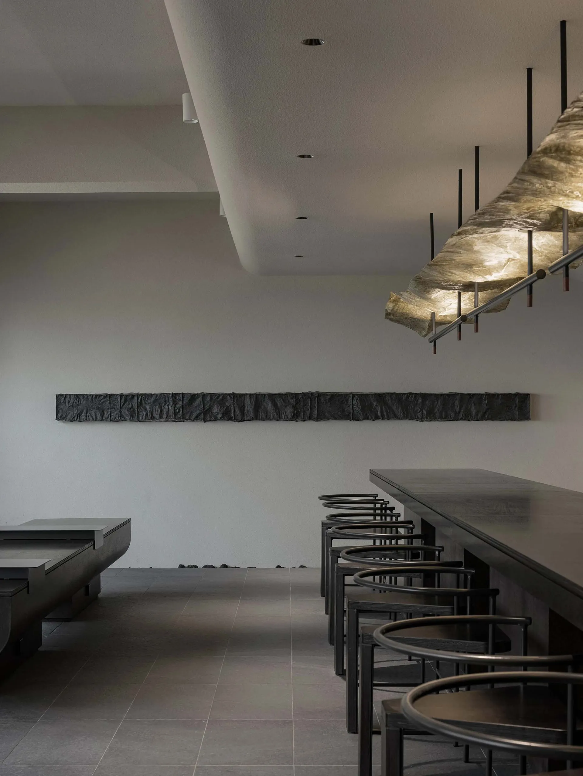 Modern restaurant interior with concrete walls, metal tables, and bar stools