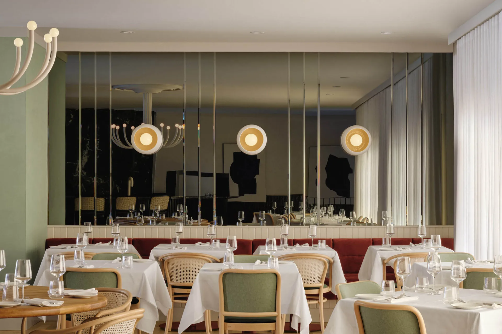 Modern restaurant interior with white tables, chairs, and pendant lights.