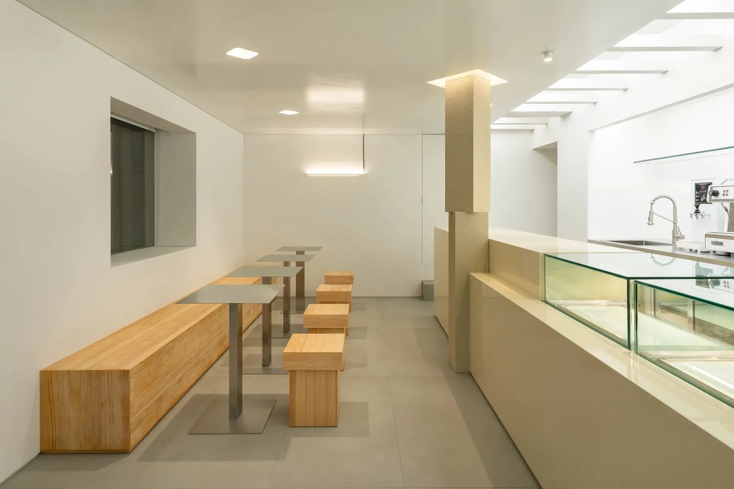 A minimalist restaurant interior with wooden benches and tables.