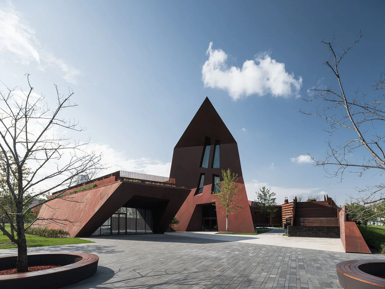 A modern, geometric building with a metallic exterior featuring large windows and a pointed roof.