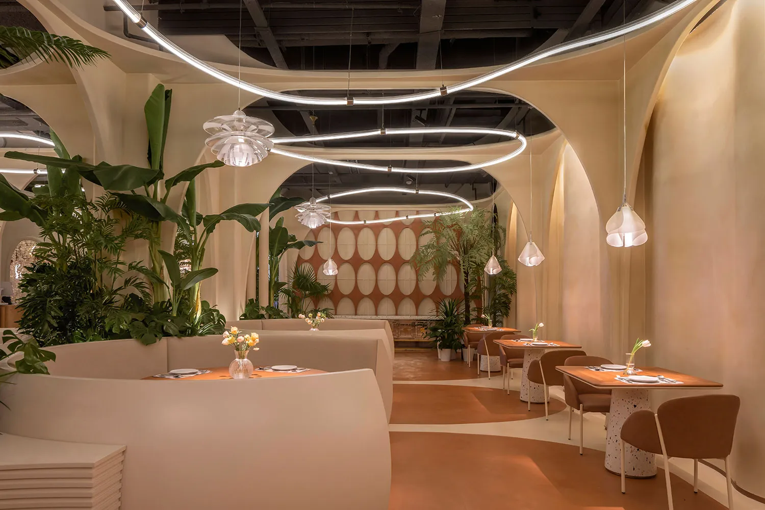 A modern restaurant interior featuring terrazzo flooring and lush green plants.