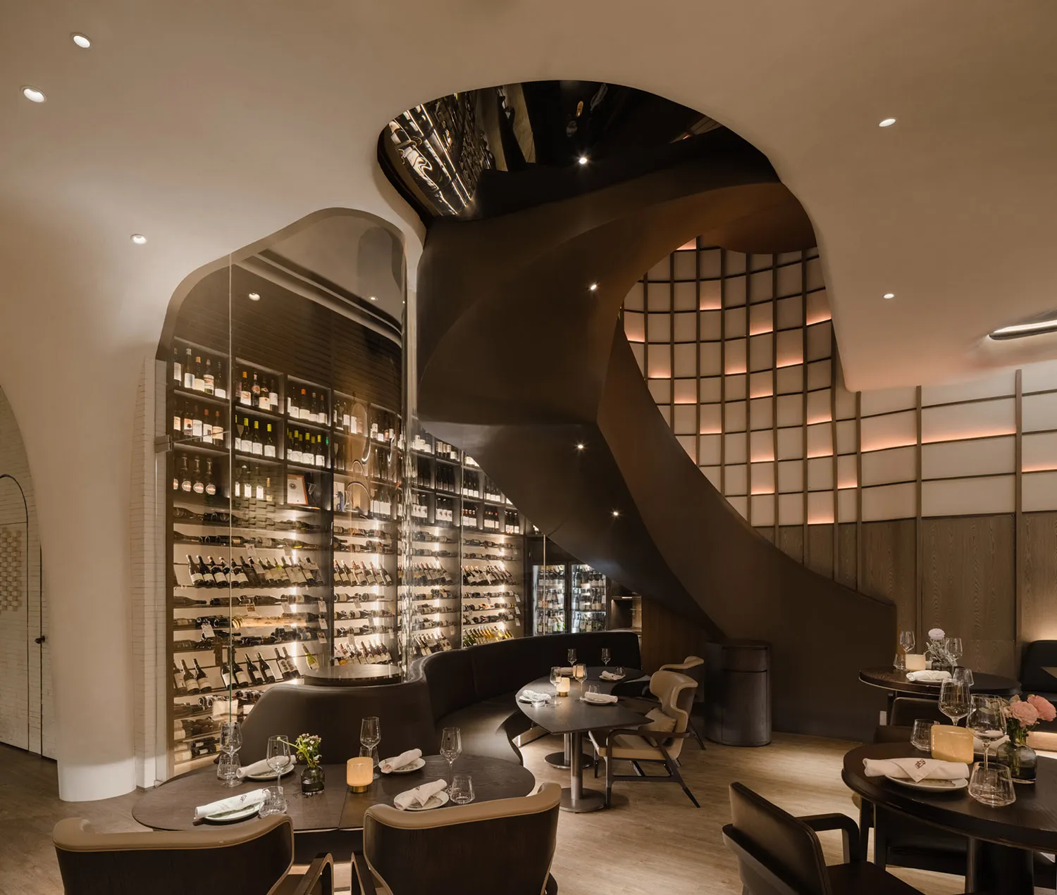 A modern restaurant with wooden tables, chairs, and a wine cellar.