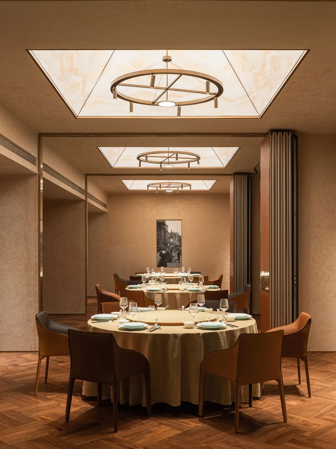 Modern dining room with round tables, chairs, and a chandelier.