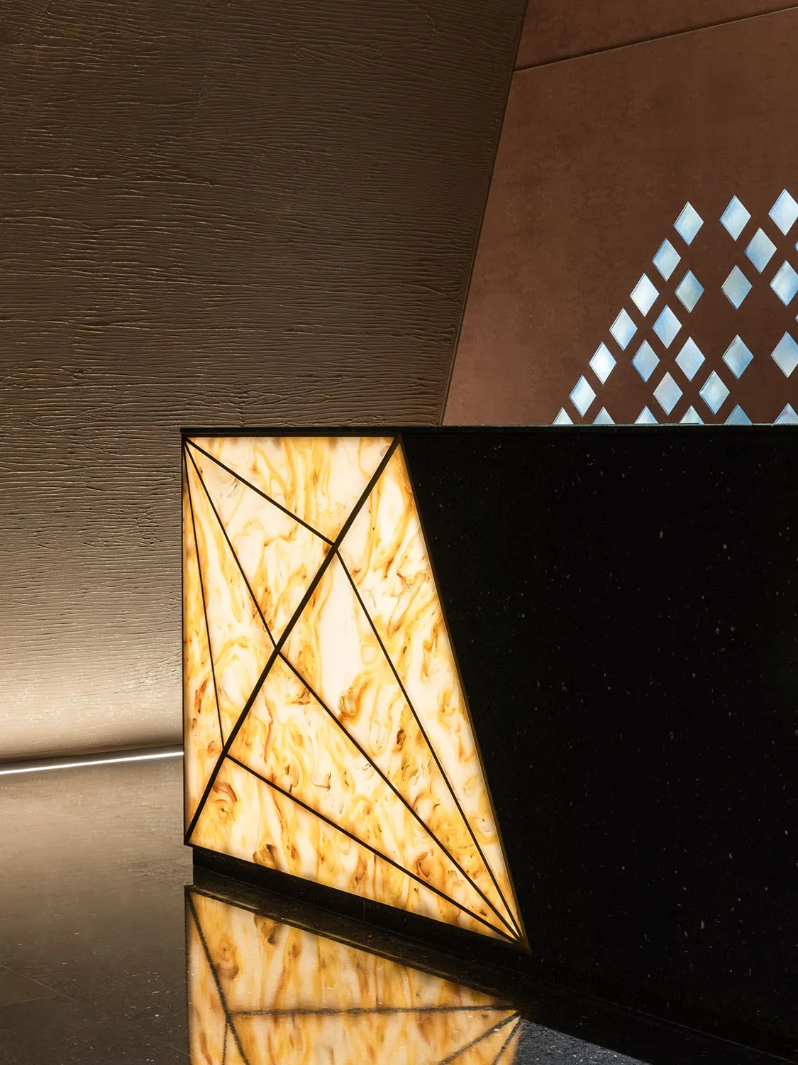 A modern reception counter featuring geometric shapes and illuminated by backlighting, with a textured marble finish.