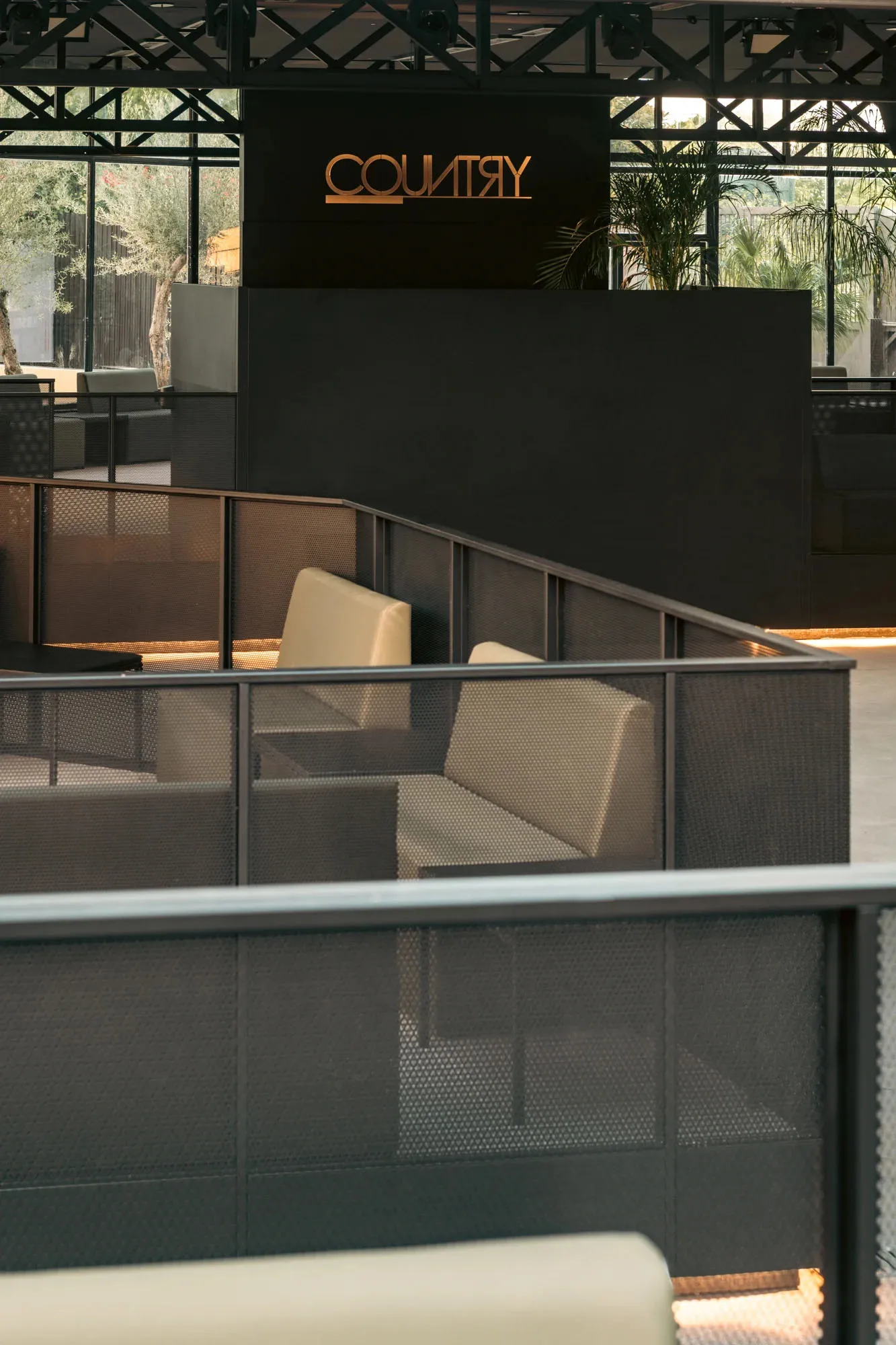 Modern restaurant interior with textured metal walls and white cushioned seating.