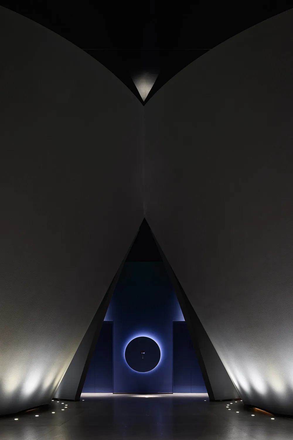A minimalistic, dark architectural interior with dramatic lighting and geometric shapes.