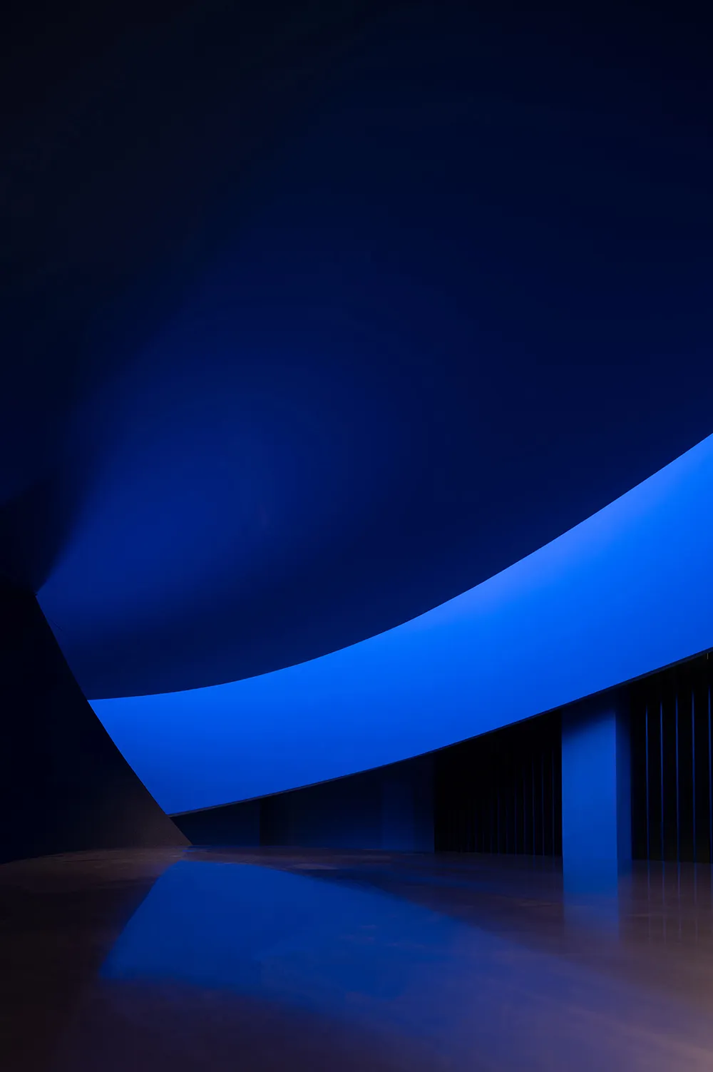 An abstract, futuristic interior design featuring bold blue lighting and geometric shapes.