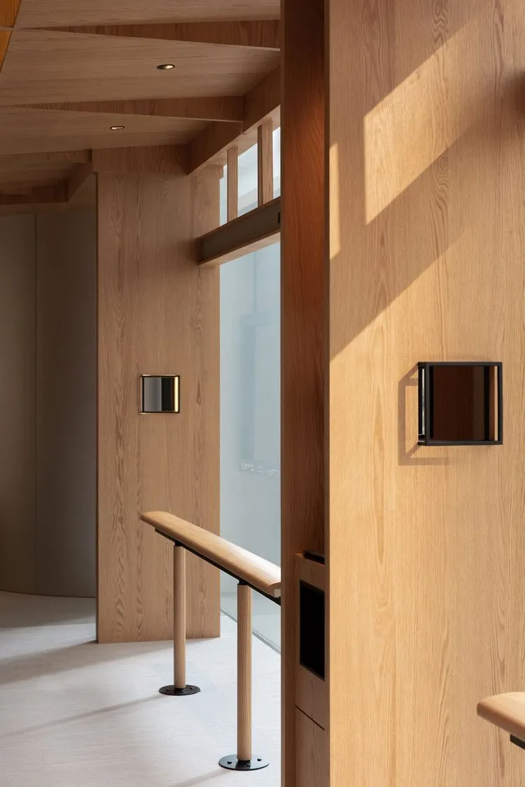 A modern, minimalist lobby interior featuring wooden walls and flooring.