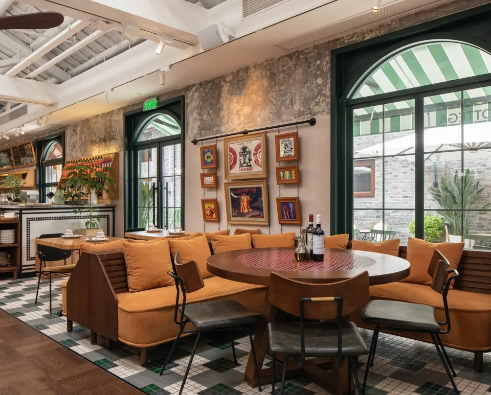 A modern industrial restaurant interior featuring wooden furniture, leather accents, and a cement wall.