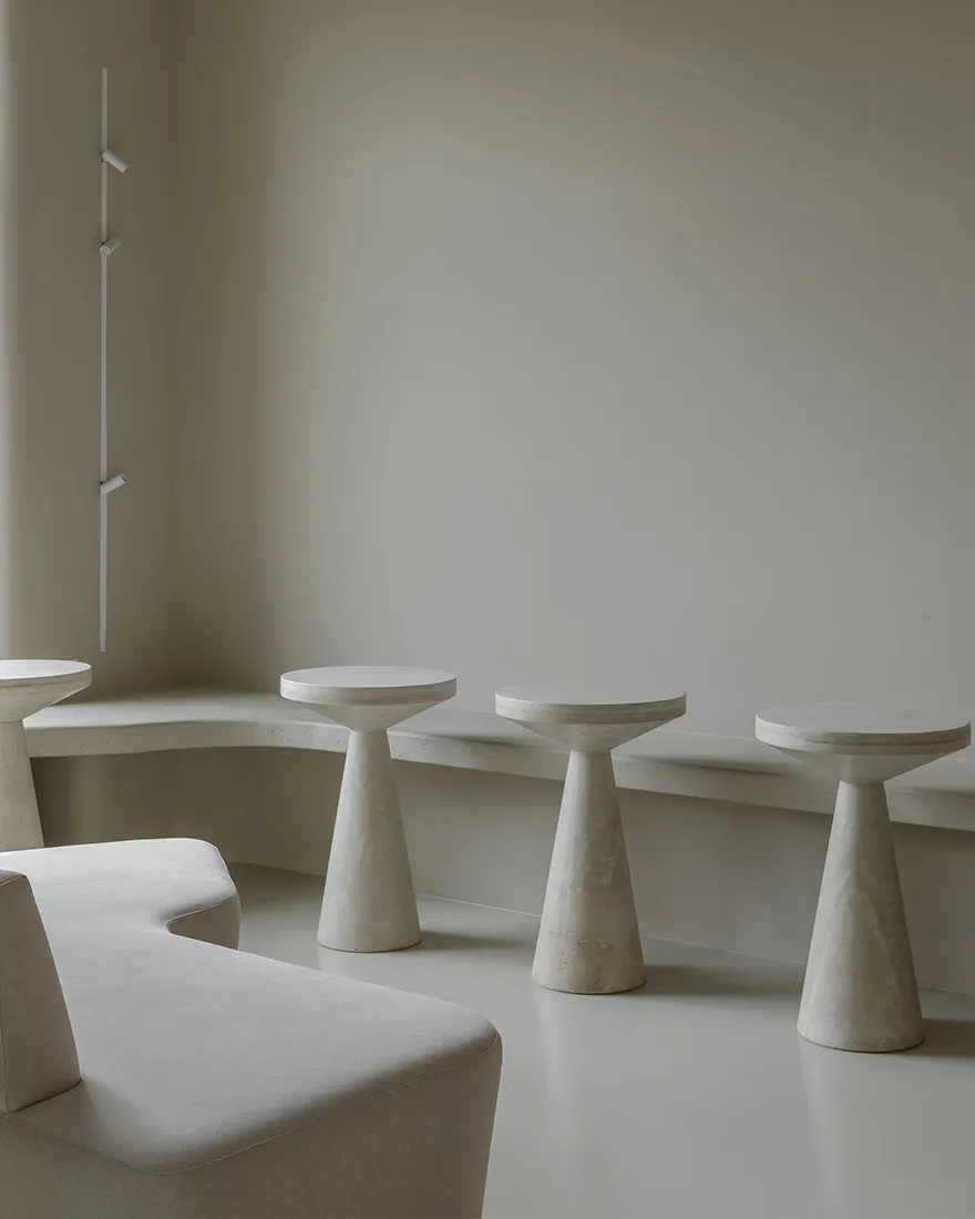 Modern minimalist seating area with concrete and marble furniture in an atrium setting.