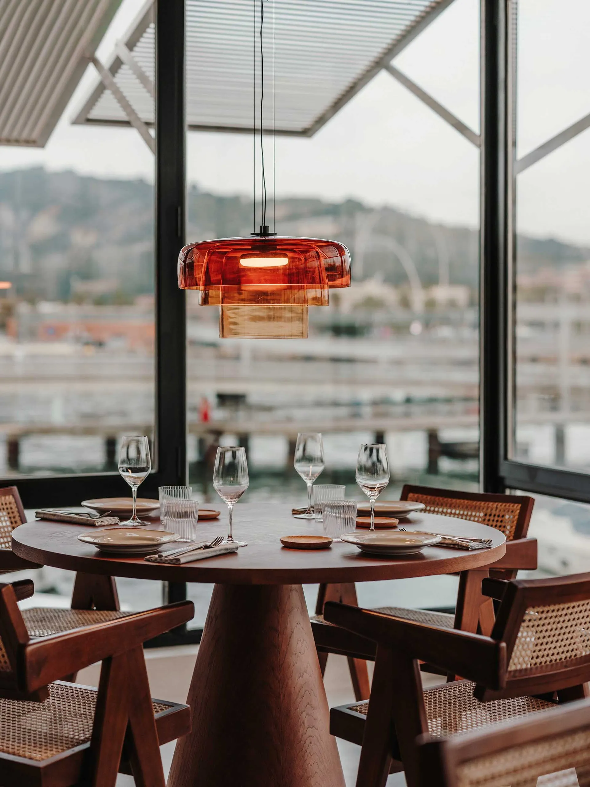 Modern restaurant setting with wooden furniture and orange light fixture.
