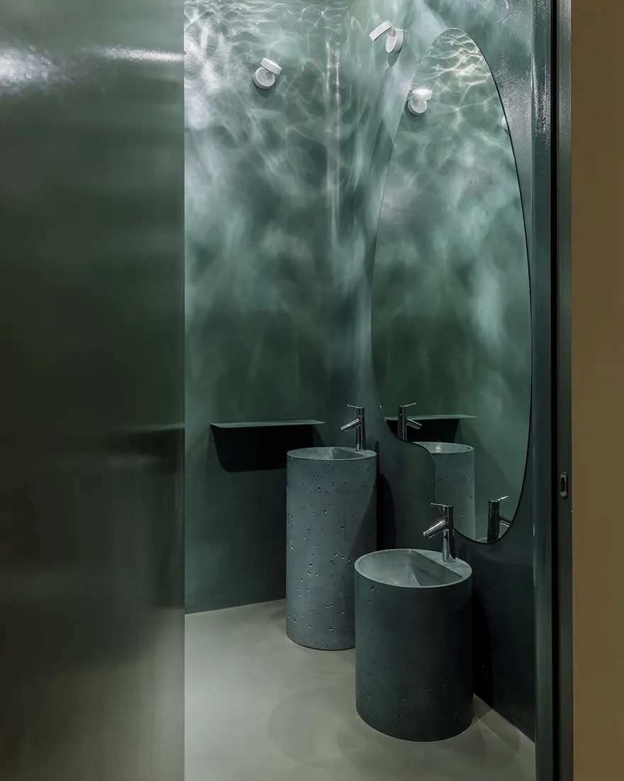 A modern bathroom featuring concrete sinks and glass walls