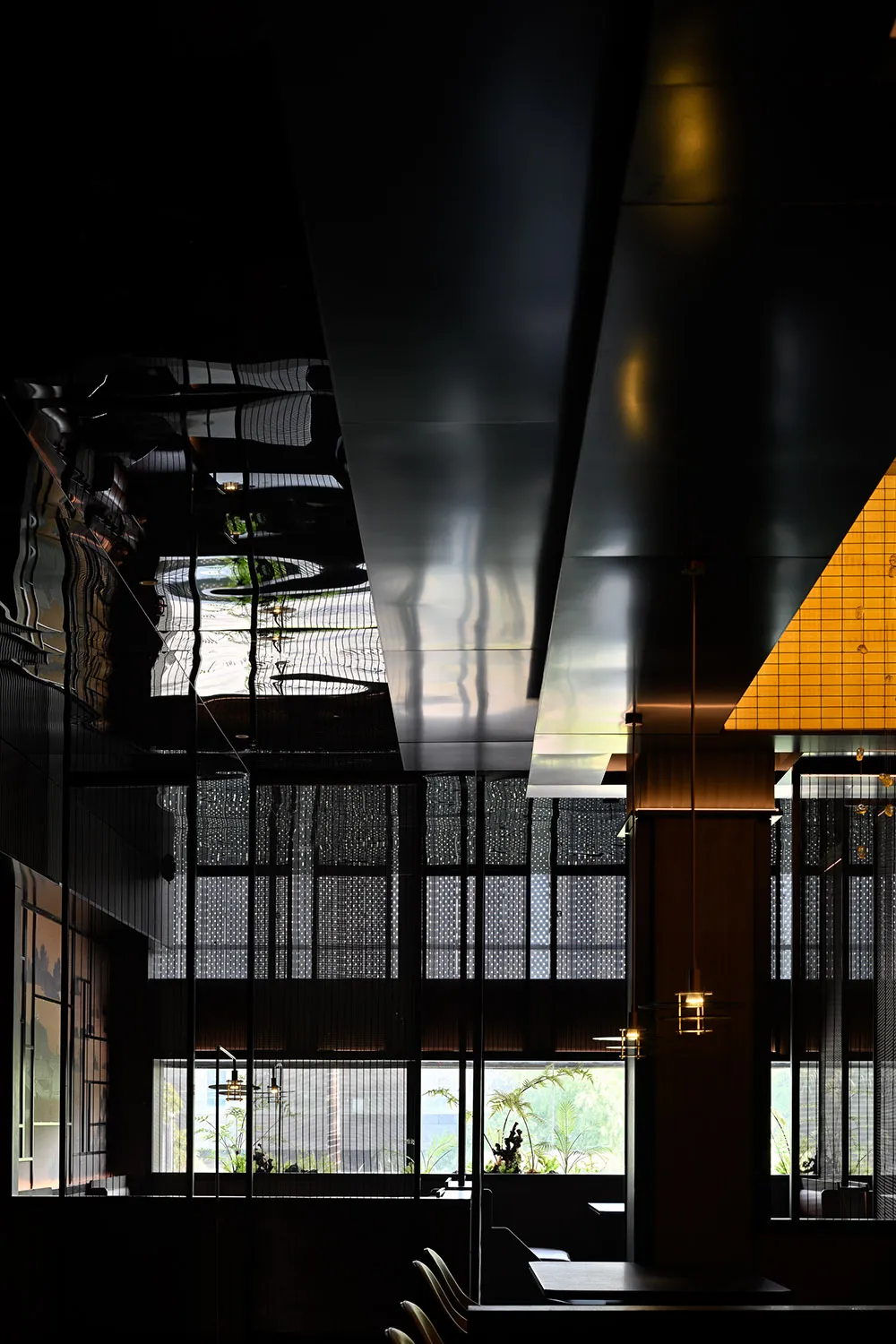 Industrial-style restaurant interior with metallic ceiling and glass windows.