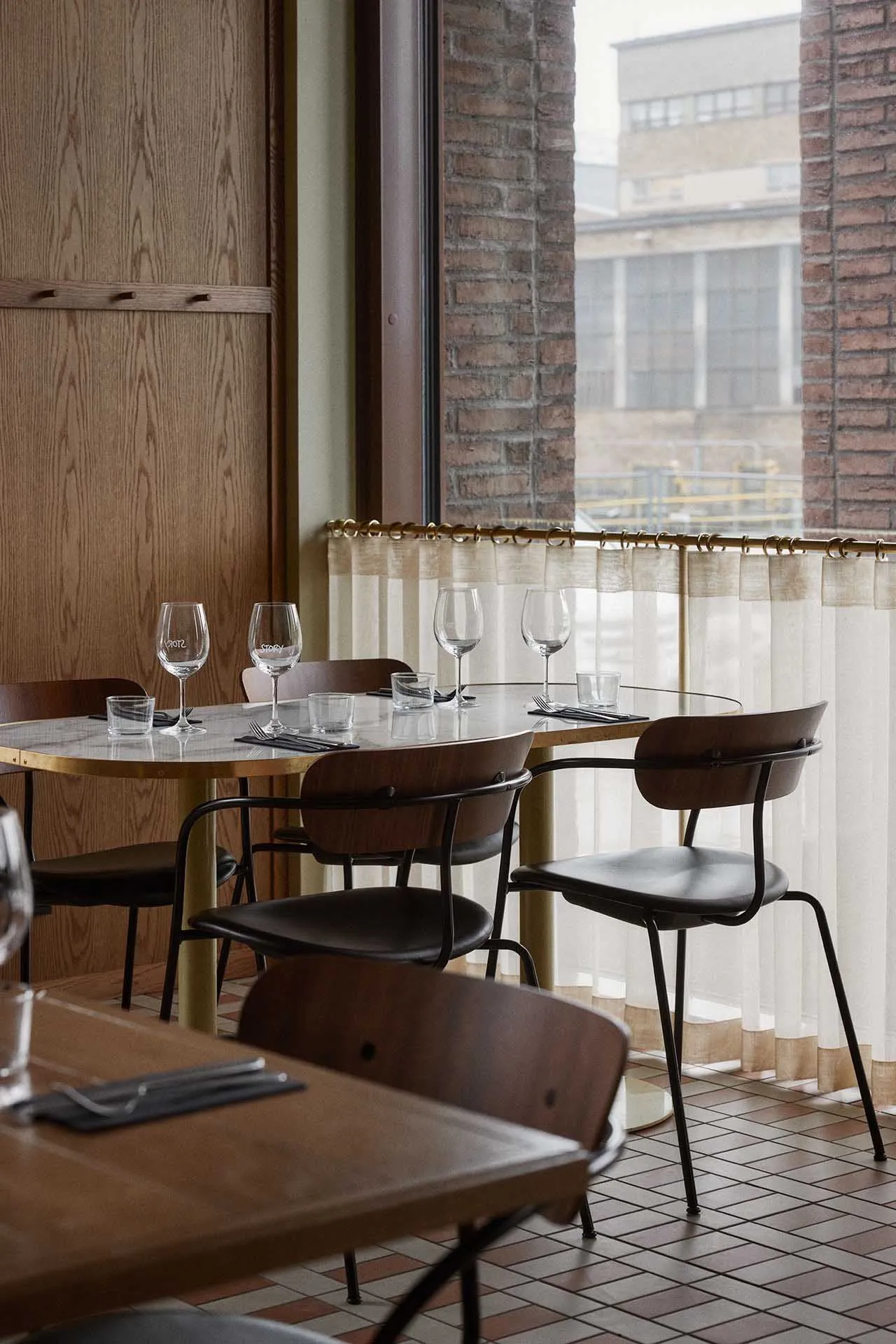 An industrial-style restaurant interior featuring marble countertops and wooden chairs.