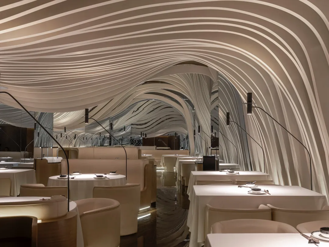 A modern restaurant interior with textured ceiling panels and soft lighting.