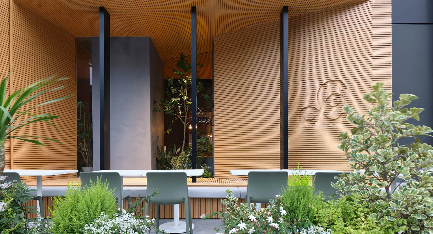 Outdoor seating area with green chairs and white tables at a restaurant with a modern design in wood.