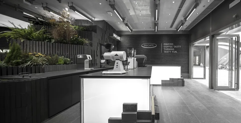 Interior of a modern coffee shop featuring a counter made of concrete with industrial design elements.