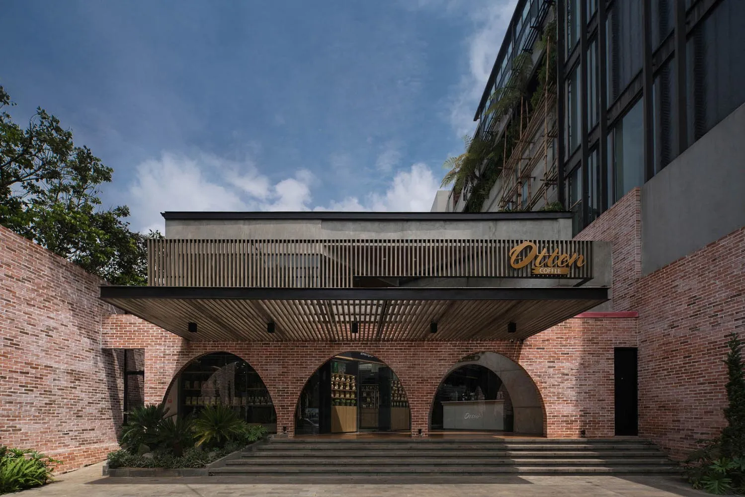 Modern coffee shop exterior with brick walls, concrete overhang, and wooden accents.