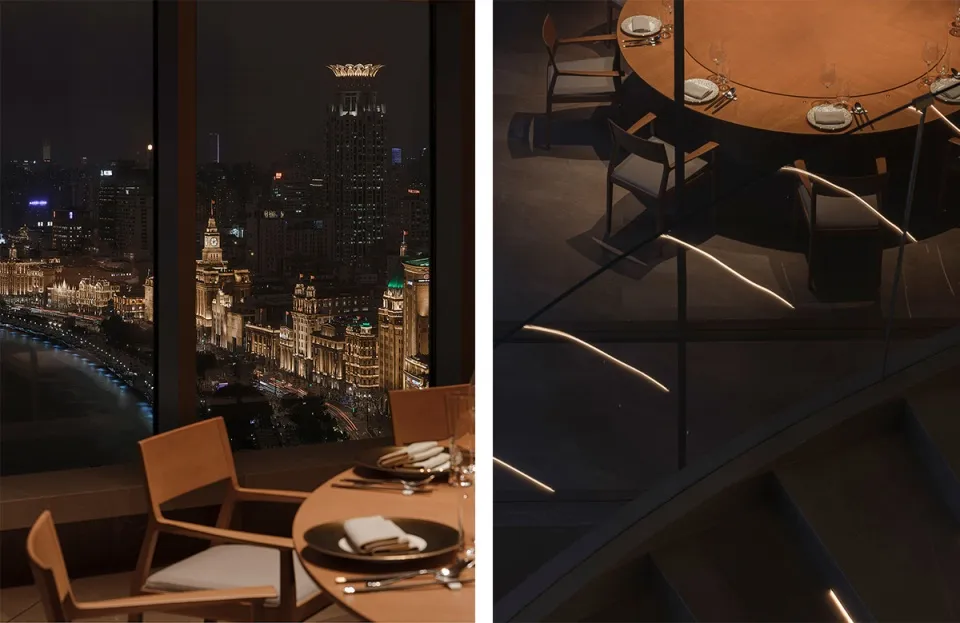 Modern restaurant dining area with a view of the cityscape at night, featuring wooden tables, chairs, and place settings.