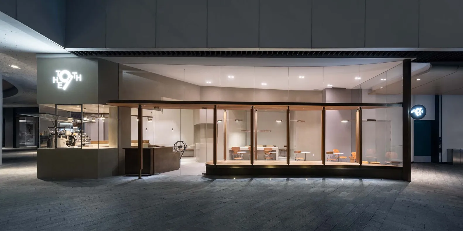 Modern cafe interior with glass walls and wooden furniture.