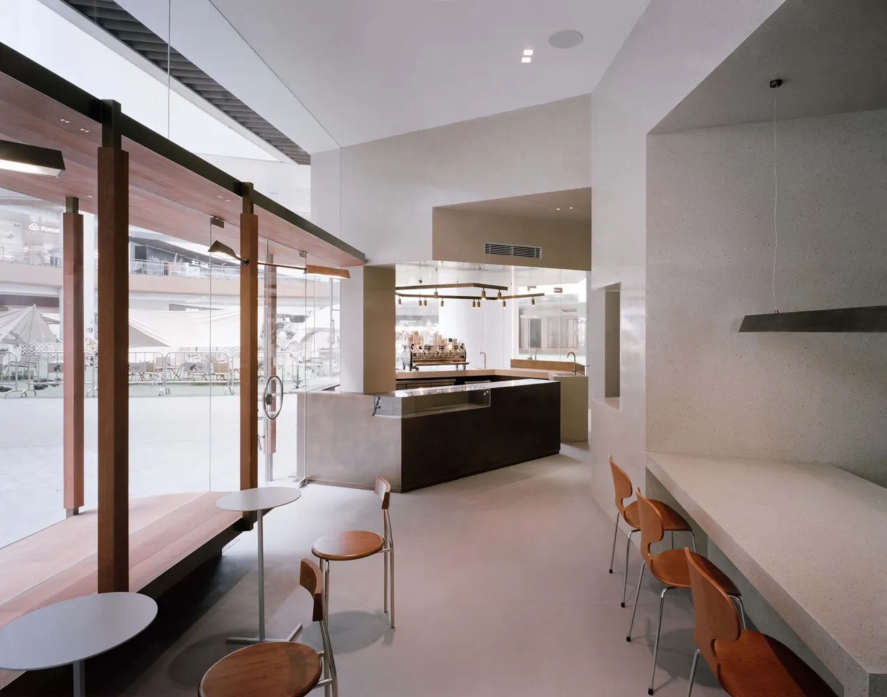 A sleek, minimalist coffee shop designed with concrete and wood materials, featuring a contemporary interior layout.