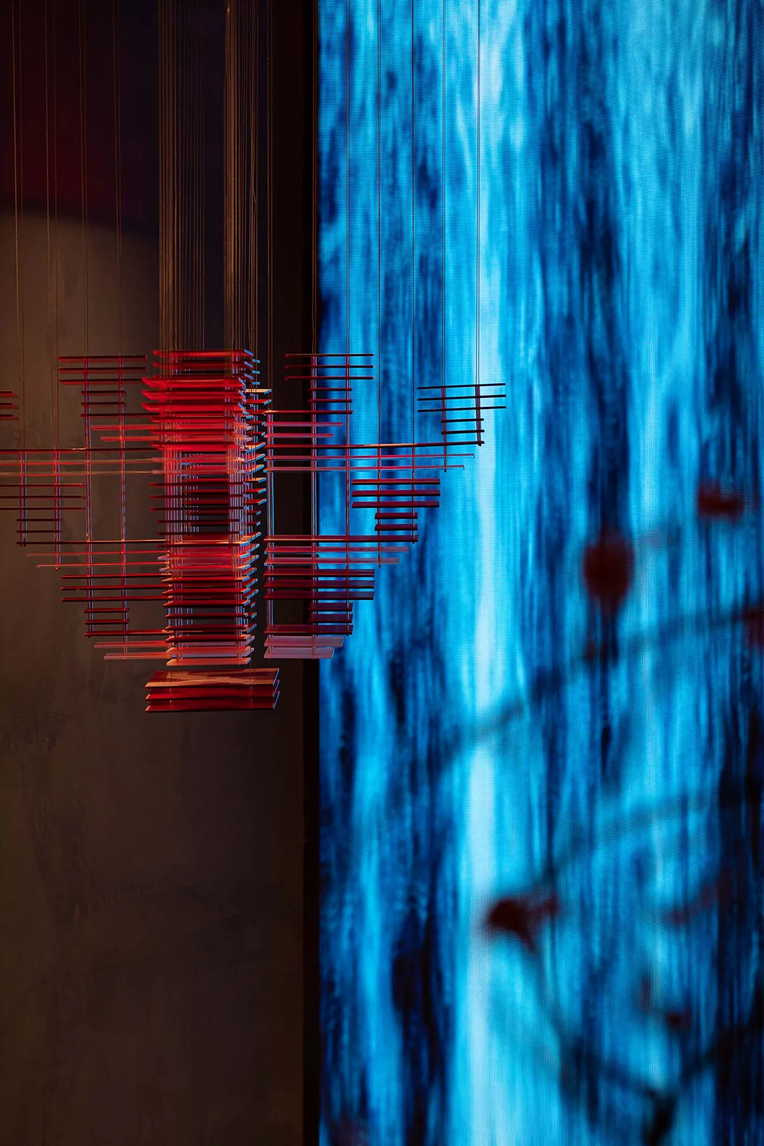 Minimalist art installation featuring metallic rods on a blue background.