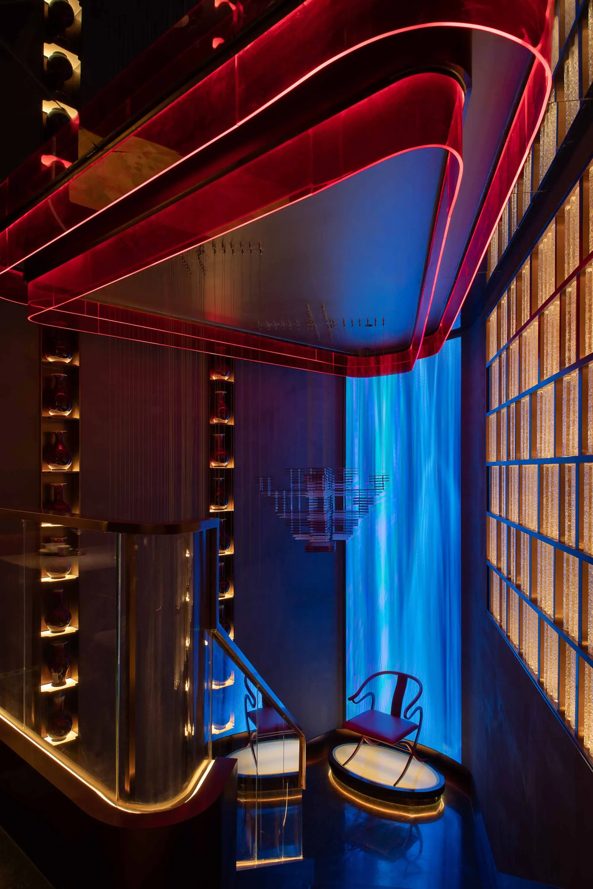 Modern hotel lobby with glass and metal design elements and red and blue lighting