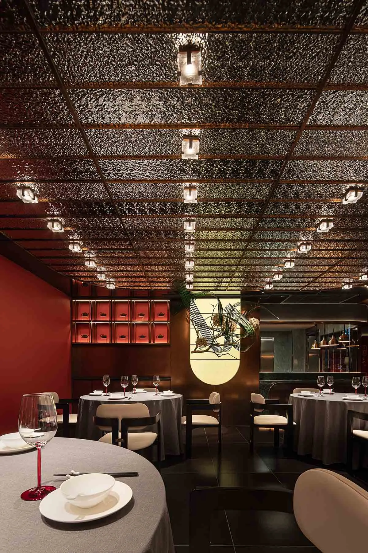 A modern restaurant interior with metallic ceiling, round tables, and chairs.
